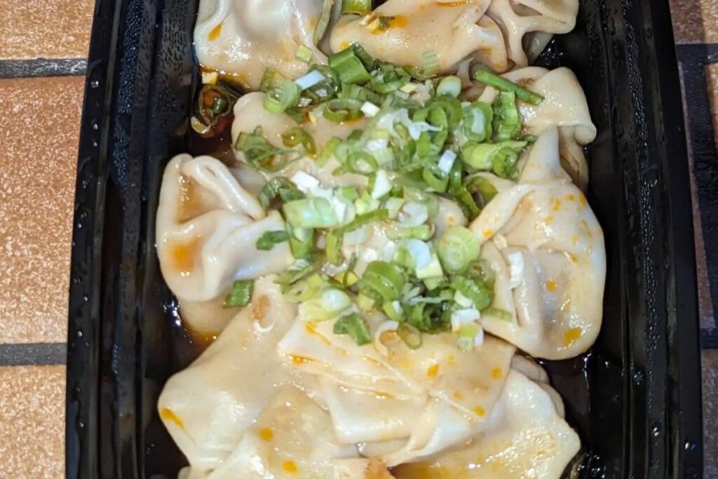 Pork wontons topped with scallions and chili sauce