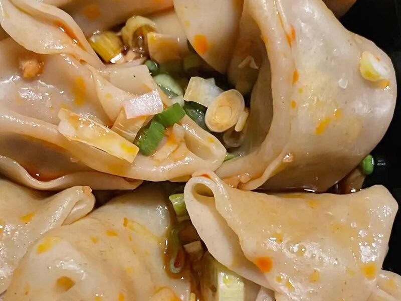 Spicy pork wontons in chili sauce with scallions